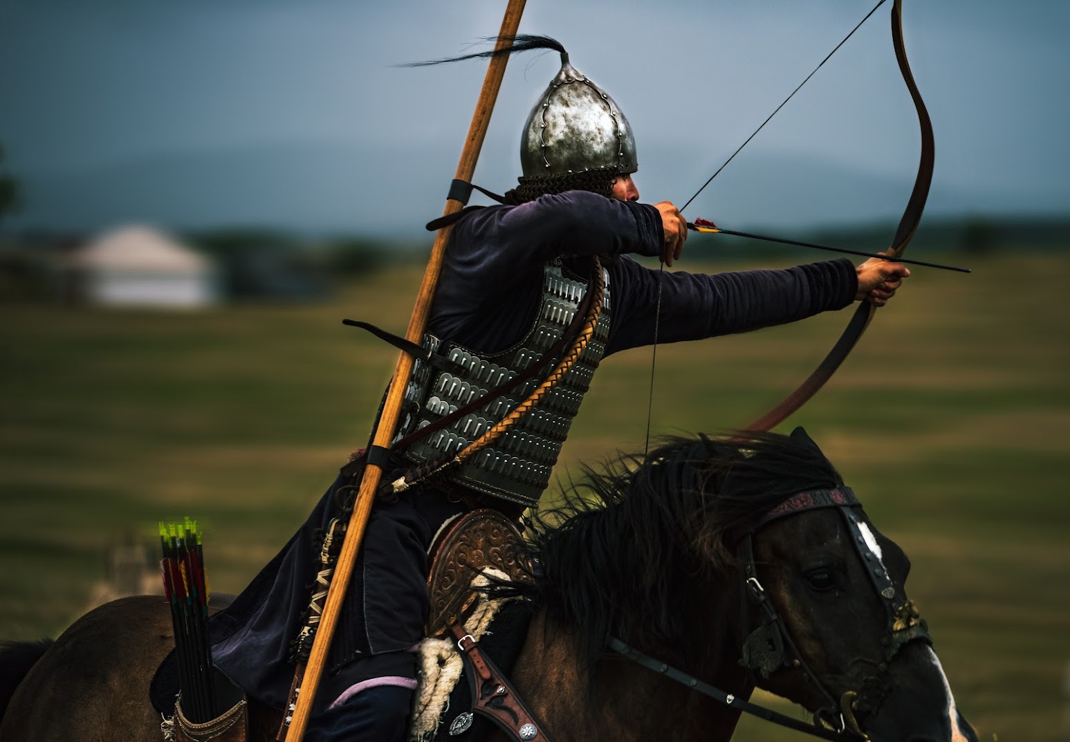 A mounted archer at full gallop drawing a recurve bow